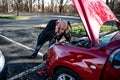 A driver catch his head trying to start a broken car with jumper cables. Royalty Free Stock Photo