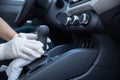 Driver disinfecting the gearshift of a car with a rag for covid-19 prevention