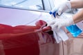 Driver disinfecting the handle of a car door with spray and a rag