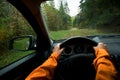 Driver dressed bright orange jacket driving a modern off road left hand drive LHD car on the mountain green forest country road. Royalty Free Stock Photo