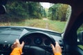 Driver dressed bright orange jacket driving a modern off road right hand drive RHD car on the mountain green forest country road. Royalty Free Stock Photo