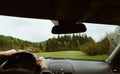 Driver driving a modern off road left hand drive LHD car on the mountain green forest country road at rainy moody day. POV inside Royalty Free Stock Photo