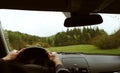 Driver driving a modern off road left hand drive LHD car on the mountain green forest country road at rainy moody day. POV inside Royalty Free Stock Photo