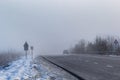 Driver of almost empty grey foggy misty rainy highway intercity road with low poor visibility on cold spring autumn morning. Royalty Free Stock Photo