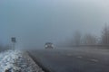 Driver of almost empty grey foggy misty rainy highway intercity road with low poor visibility on cold spring autumn morning. Royalty Free Stock Photo