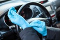 Driver getting his blue protective gloves before touching steering wheel. Protection against the Covid-19 virus