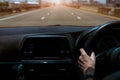 Driver hand holding steering wheel for control car. Inside view of car. Dashboard and windshield. Driving car on concrete road