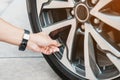 Driver hand inflating tires of vehicle, removing tire valve nitrogen cap for checking air pressure and filling air on car wheel at Royalty Free Stock Photo