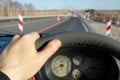 The driver hand on the steering wheel of the car against the background of the road being repaired with fences Royalty Free Stock Photo