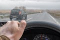 Driver hand on the steering wheel inside the car and raindrops on the windshield