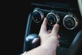 Driver hand tuning air ventilation grille, emergency flasher switch and light in modern car interior Royalty Free Stock Photo