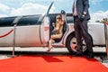 Driver helping VIP woman or star out of limo on red carpet