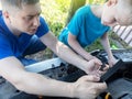 Timing belt break. Man and son near hood of car is looking for a malfunction due to which the engine does not work. Driver is Royalty Free Stock Photo