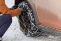 Driver installs chains on the wheel of his car in winter. Vehicle equipment for off-road and bad weather Royalty Free Stock Photo