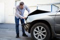 Driver man looking on wrecked car in car accident. Man regrets about fixing car headlight after auto crash. Tragedy car collision