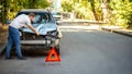 Driver man looking on wrecked car in car accident. Man regrets about fixing car headlight after auto crash. Tragedy car collision Royalty Free Stock Photo