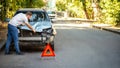 Driver man looking on wrecked car in car accident. Man regrets about fixing car headlight after auto crash. Tragedy car collision