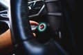 The driver palm as it presses the electric car engine start stop button with a green light illuminated