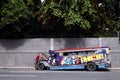 A driver parks his colorful passenger jeep and puts engine oil to his vehicle