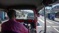 Driver with a purple shirt driving a three-wheeled Indian vehicle in the daytime