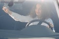 Driver in rear-view mirror. Attractive young woman in business wear looking in rear-view mirror and smiling while driving a car Royalty Free Stock Photo