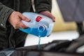 Driver refilling the blue non-freezing windshield washer liquid in the tank of the car, close-up Royalty Free Stock Photo