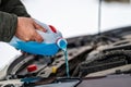 Driver refilling the blue non-freezing windshield washer liquid in the tank of the car, close-up Royalty Free Stock Photo