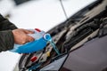 Driver refilling the blue non-freezing windshield washer liquid in the tank of the car, close-up Royalty Free Stock Photo