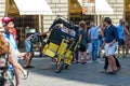 Driver repairs a rickshaw in a crowded square near the Basilica of Santa Maria del Fiore, Florence