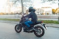 Driver riding motorcycle on empty road in beautiful autumn city. Royalty Free Stock Photo