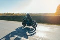 Driver riding motorcycle on empty road in beautiful autumn forest. Royalty Free Stock Photo