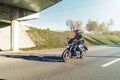 Driver riding motorcycle on empty road out of the city at beautiful autumn time. Royalty Free Stock Photo