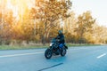 Driver riding motorcycle on empty road in beautiful autumn forest. Royalty Free Stock Photo