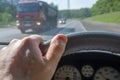 Driver hand on the steering wheel of a car and a passing truck Royalty Free Stock Photo