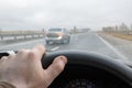 Driver`s hand on the steering wheel of a car that is driving on the highway