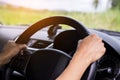 Driver`s hands on the steering wheel inside of a car with beautiful green forest perspective. Royalty Free Stock Photo