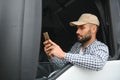 A driver sitting inside the semi-truck while looking through the open window with multiple trucks parked in the