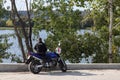 The driver of a sports motorcycle stands near the river