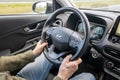 Driver at steering wheel while driving a car. Interior of Hyundai Kona hybrid