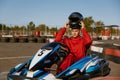 Driver taking off protective helmet while sitting at kart race car Royalty Free Stock Photo