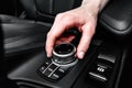 Driver turning media and navigation control button of a modern car. Car interior details.