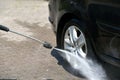 The driver washes the car wheels with high pressure water
