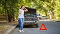 Driver woman in front of wrecked car in car accident. Scared woman in stress holding her head after auto crash calling to auto Royalty Free Stock Photo