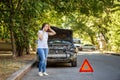 Driver woman in front of wrecked car in car accident. Scared woman in stress holding her head after auto crash calling Royalty Free Stock Photo