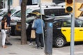 Drivers Stuffing Suitcases into the Trunk of the Cab in the Street and Couple of Tourists ready to Leave