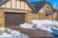 Driveway and snowy yard in front of garage door of home with stone brick wall Royalty Free Stock Photo