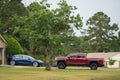 Driveway with Tesla Model 3 electric car and red lifted pick up truck Royalty Free Stock Photo