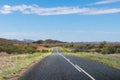 Driving across the MacDonnell ranges. Mountains at the background. Empty road, no cars, no signs. Green vegetation and bush on the