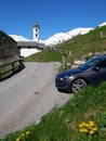 Driving around italian dolomites - classical view car church and mountains in a background