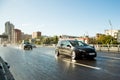 Driving in big city. Drive tuning car in rain on asphalt wet road. Clouds and sun